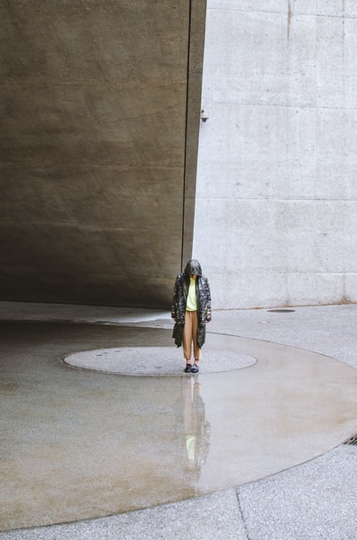 穿着黑白衣服的女人站在灰色的水泥地上